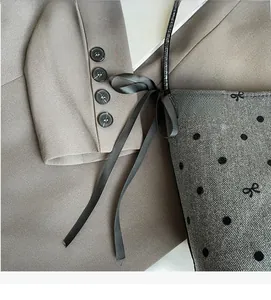 Detail of grey herringbone fabric tote bag with polka dots, bows and black silk ribbons