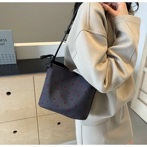 Detail of dark grey canvas bucket bag with red polka dots and black ribbon bow