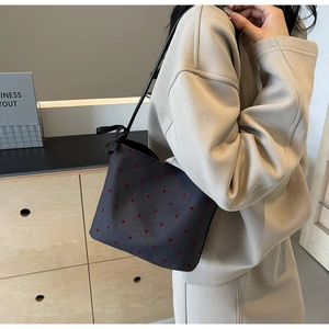 Detail of black canvas tote bag with red polka dots and decorative silk ribbon bow
