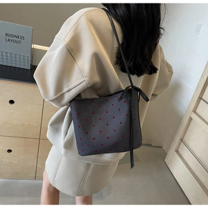 Detailed view of dark grey polka dot bucket bag with stylish black ribbon bow decoration