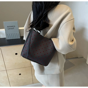 Detail of grey canvas bucket bag with red heart prints and black ribbon bow accent