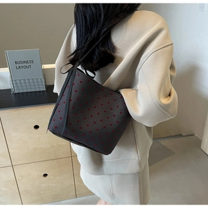Detail of grey canvas shoulder bag featuring red heart patterns and black ribbon bow