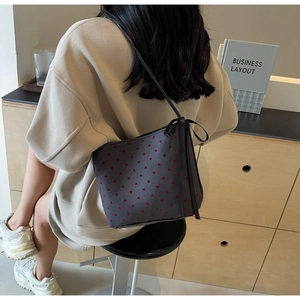 Detail of dark grey canvas tote bag featuring red heart patterns and a black ribbon bow