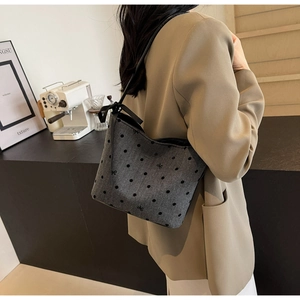 Detail of grey canvas shoulder bag with black polka dots and side ribbon bow accents