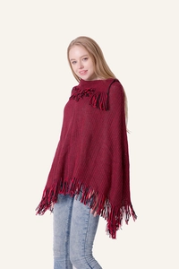 Detailed close-up of red and black knit poncho sweater showing fringed tassels and texture