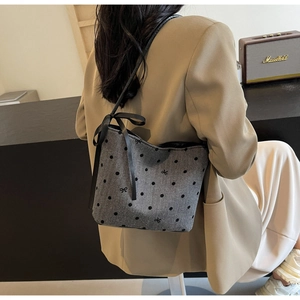 Detail of grey polka dot hobo bag with long black satin ribbons and woven bow decor