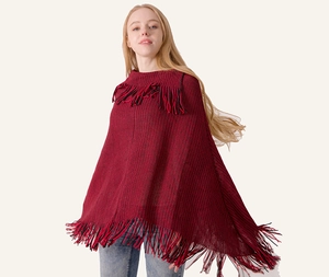 Detail of red and black knit poncho cape featuring thick texture and long fringe trim
