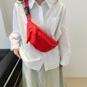 Vibrant red sporty crossbody waist bag with adjustable strap worn by model on white shirt