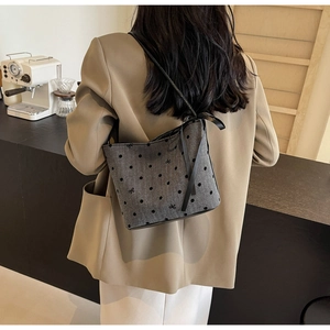 Detail of gray bucket bag with black polka dots and ribbon bow decoration on shoulder