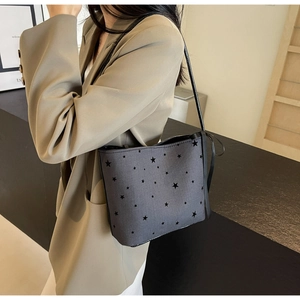 Detail of dark grey star print canvas tote bag with black leather straps on a model