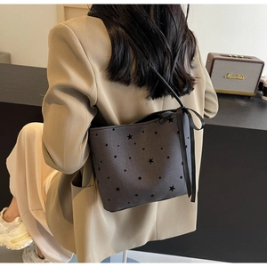 Detail of dark grey bucket bag featuring black star prints and a satin ribbon bow