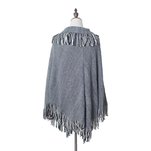 Detail of black and white geometric knit poncho with dense fringe on a mannequin