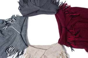Detailed close-up of knit texture and tassels on multiple color winter ponchos