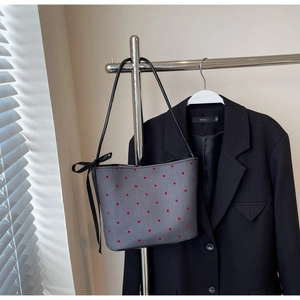 Close-up of gray polka dot hobo bag with a black ribbon bow on a silver hanger