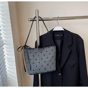Detail of gray polka dot underarm bucket bag with bow embroidery and silk ribbon