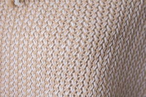 Macro view of knit texture with intertwined white and light brown yarns and refined pattern