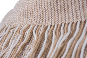 Close-up of beige V-pattern knit texture and dense tassel fringe detail on a shawl