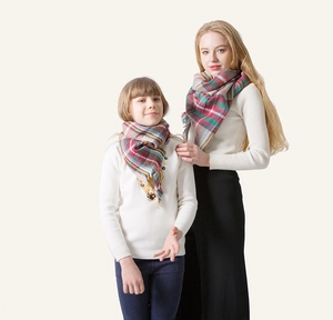 Detail of red and green plaid cashmere-feel scarf with fringe edges for parent and child