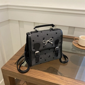 Grey herringbone canvas backpack with black polka dots and metallic bow accent