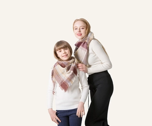 Detail of plaid tassel scarf showing warm beige and brown tones for parent and child