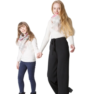 Close-up of mother and daughter matching pink plaid cashmere-like scarves with fringe details