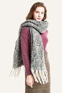 Detailed view of gray and white chunky knit scarf with long white fringe tassels