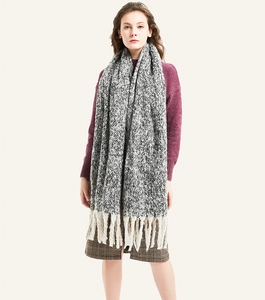 Close-up of thick chunky knit scarf with multi-color weave and large cream tassels
