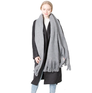Solid grey soft winter scarf with long tassels paired with a stylish black wool coat