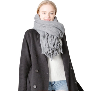 Classic grey long fringe scarf in thick wool-like knit worn with black winter coat