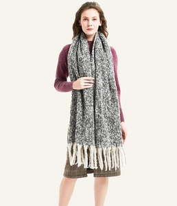 Detail of thick white tassels and mixed knit texture on an oversized scarf