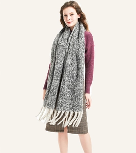 Detailed close-up of thick black and white knit scarf with chunky cream tassels texture
