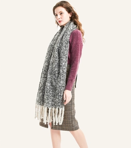 Detail shot of winter knit scarf with grey tweed texture and cream chunky fringe tassels