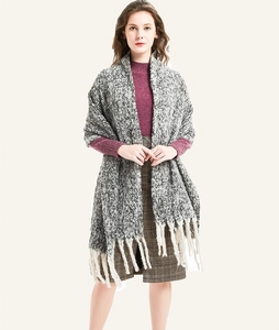Close-up of grey and white knit shawl featuring thick texture and long tassels