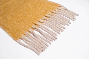 Close-up of ginger yellow winter scarf with soft brushed texture and thick cream tassels