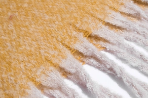 Detailed close-up of thick gradient knit scarf with fringe tassels in yellow and pink