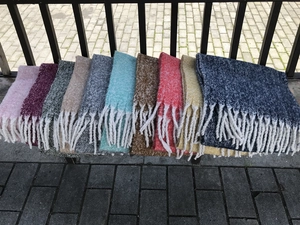 Detailed macro view showing thick boucle texture and twisted white fringe of the winter scarves