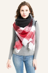 Detail of red and black plaid oversized scarf featuring soft fabric and fringe edges