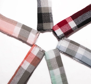 Flat lay of multiple color options for soft plaid scarves featuring fringe edge details
