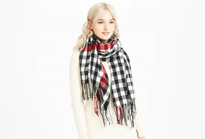 Close-up of the soft knit texture and fringe detail on the red plaid tassel scarf