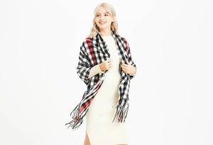Detail of red and black plaid scarf with tassels on a knit dress for autumn
