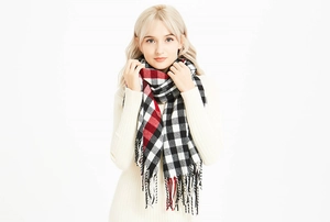 Close-up of winter plaid scarf with red, black and white checkered pattern and tassels