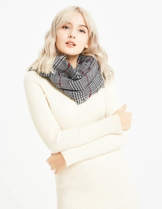 Detailed view of winter houndstooth scarf with red accents and soft fringe edges