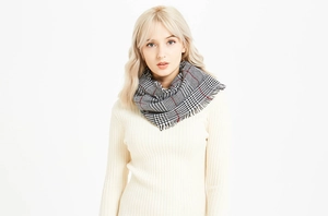 Close-up of black and white houndstooth cashmere scarf with red lines and fringed edges