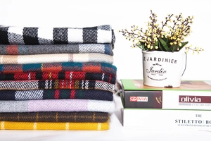 Detailed stack of assorted plaid cashmere feel scarves with soft fringe and diverse patterns