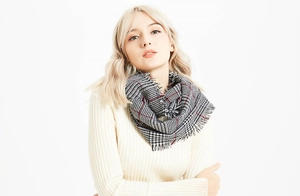 Detailed view of classic houndstooth scarf with red accents and soft fringe edges