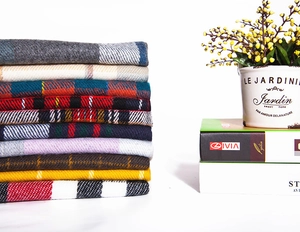 Close-up of stacked colorful plaid scarves with soft fringe and classic Scottish patterns
