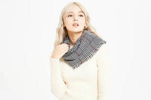 Detail of houndstooth scarf with red, black and white plaid pattern and fringe edges