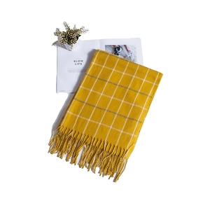 Detail view of yellow plaid scarf with soft tassels and cozy knit texture