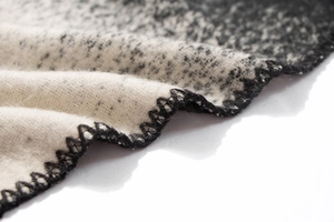 Detailed view of thick black and white gradient knit fabric with hand-stitched edging