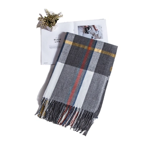 Detail of plaid scarf with tassels in grey, cream, and yellow on a white background